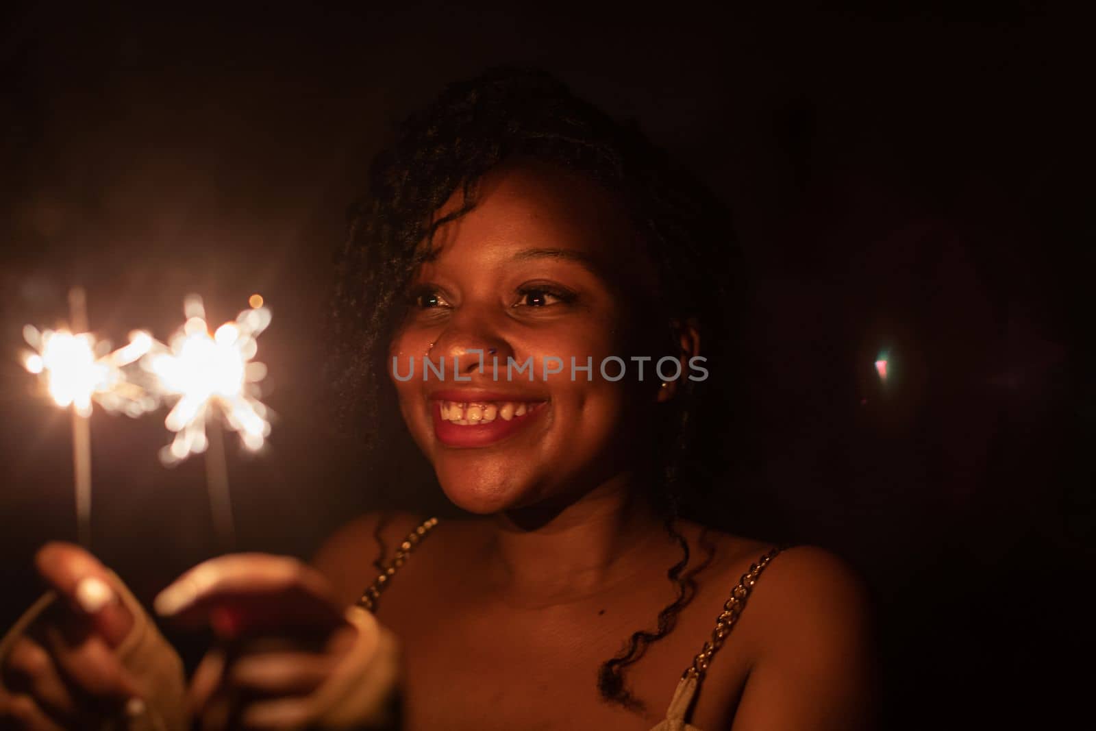 New Year's Eve fun with cold fires. An African woman and her wonderful smile. Happiness and joy is drawn on the young girl's face.
