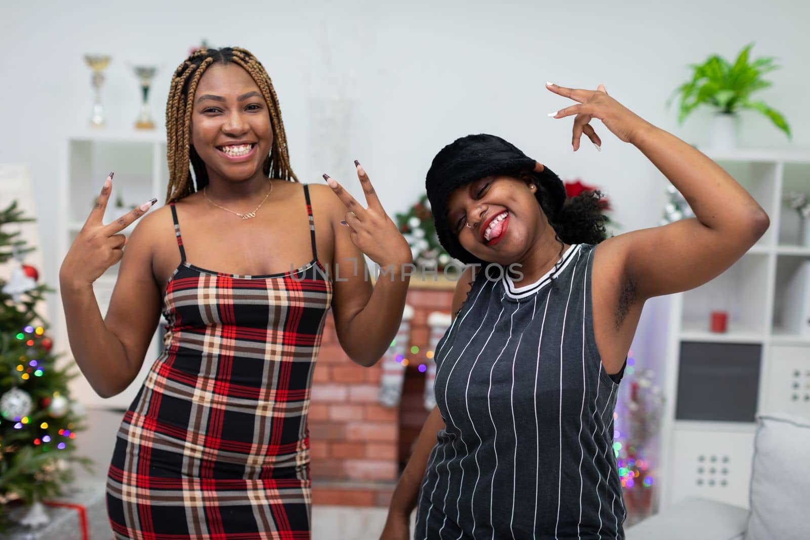 Hands in the air. Laughter and satisfied faces. African women rejoice. A room decorated for Christmas. Energetic scene during Christmas Eve.