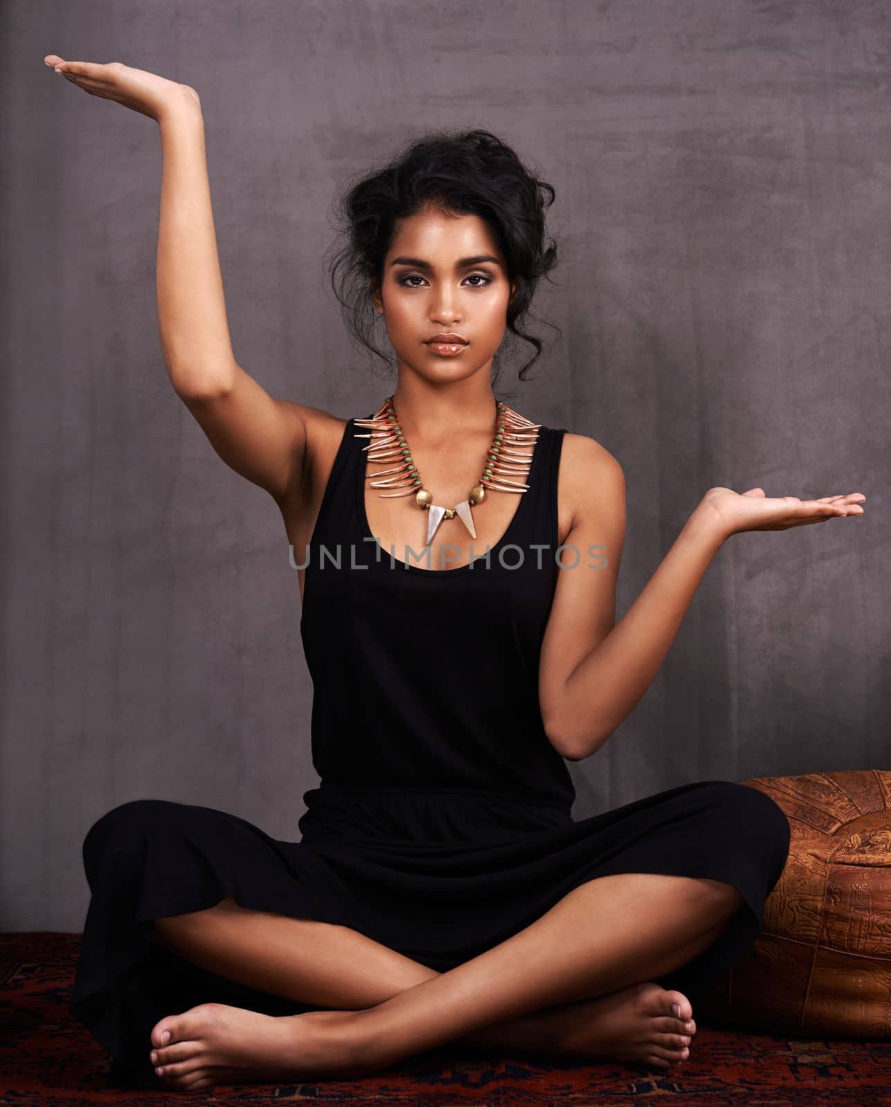 Fit never looked this stunning. Studio portrait of a beautiful young woman posing indian style against a gray background. by YuriArcurs