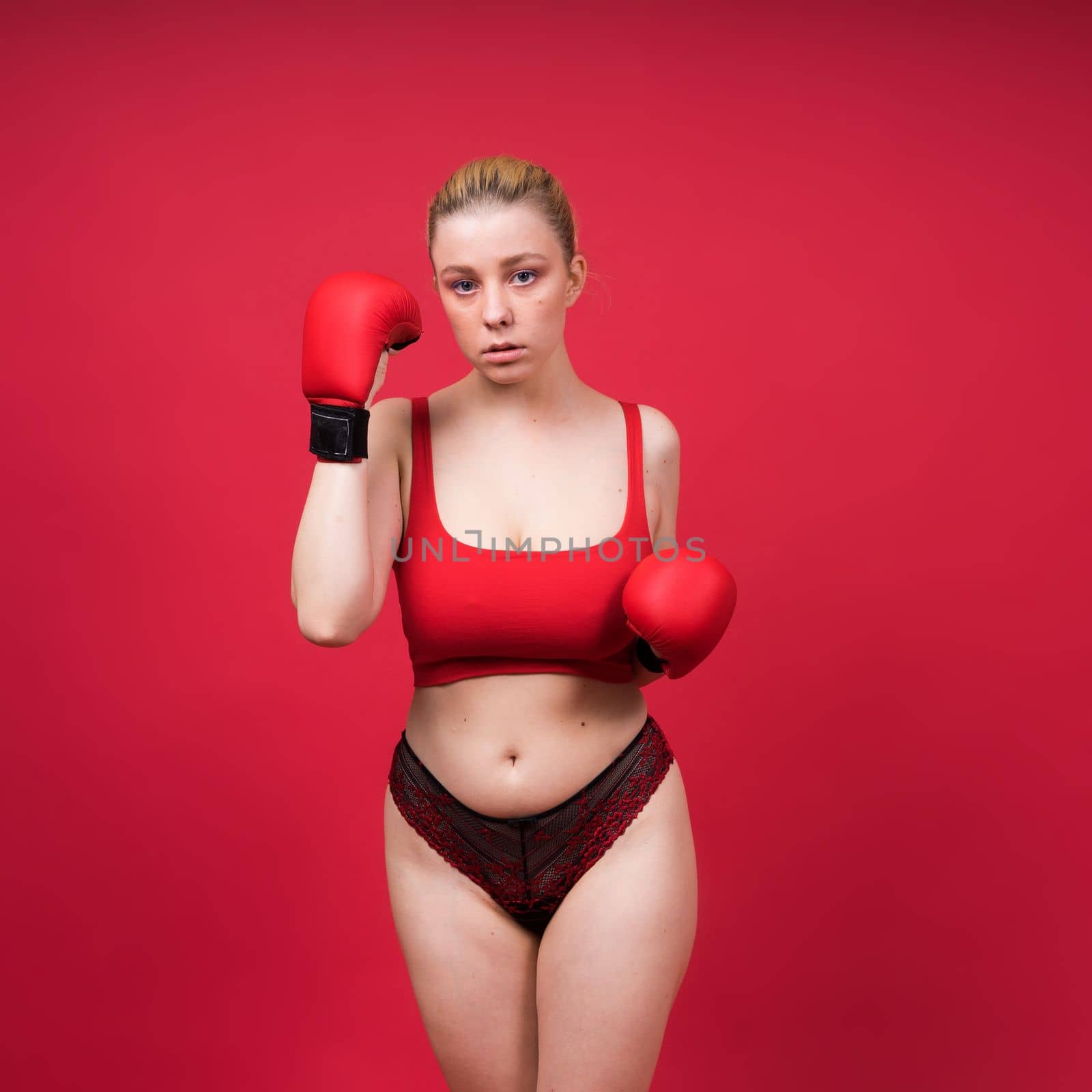 Boxer, seductive confident female boxer with gloves studio, sporty woman posing looking to camera.