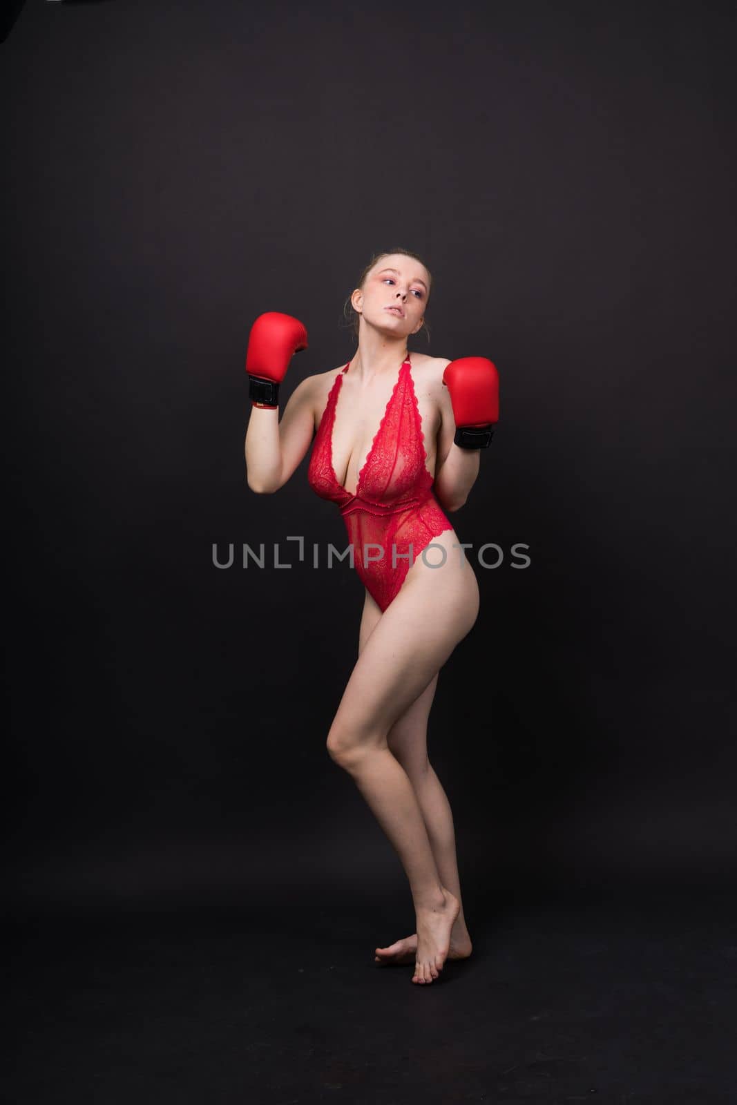 Boxer, seductive confident female boxer with gloves studio, sporty woman posing looking to camera.