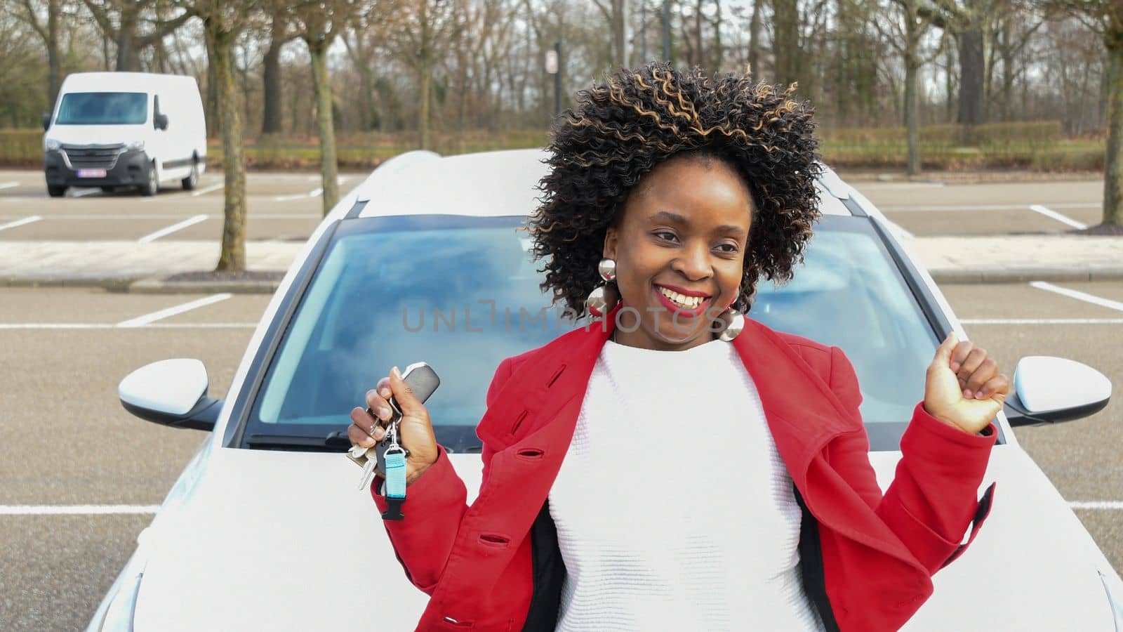 a cheerful african american woman stands next to the car and holds the keys to it in her hand, high quality photo, High quality photo