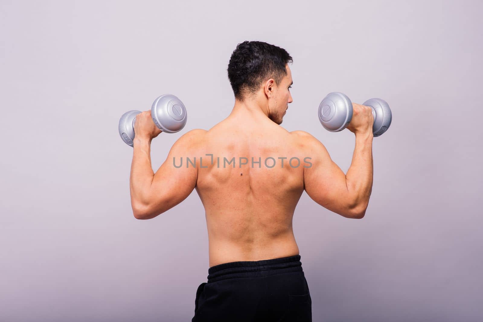 Portrait young fitness sporty strong man barechested muscular sportsman isolated on grey dark.