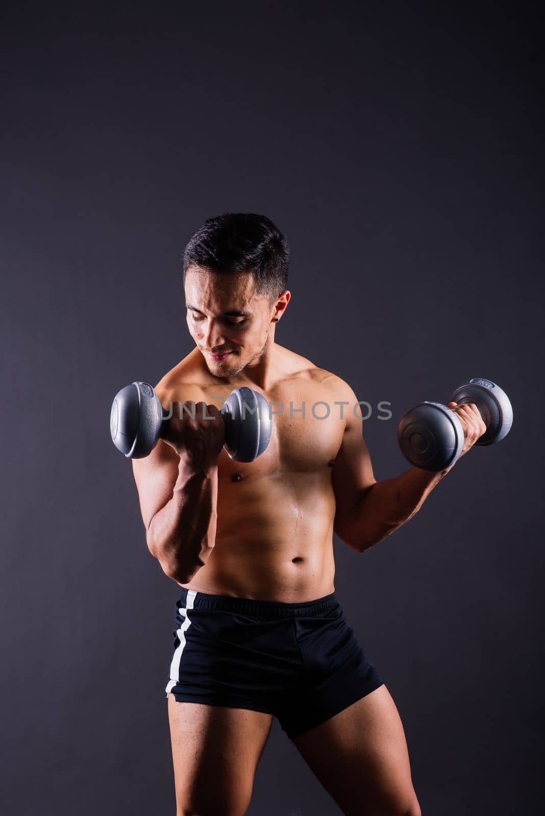 Portrait young fitness sporty strong man barechested muscular sportsman isolated on grey dark.