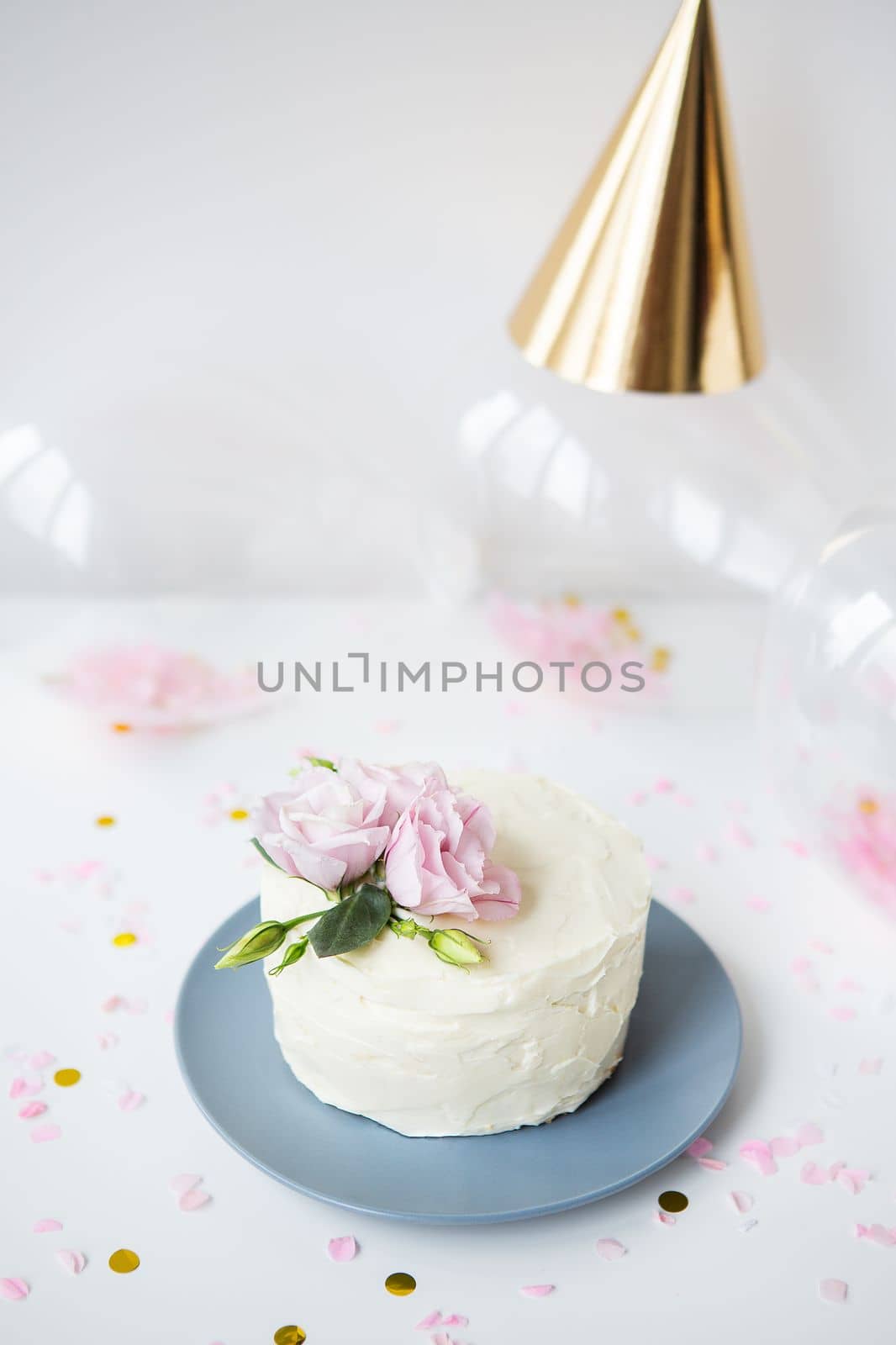 Very beautiful small white cake decorated with natural flowers eustoma on the background candy, balloons, cap. Holiday concept