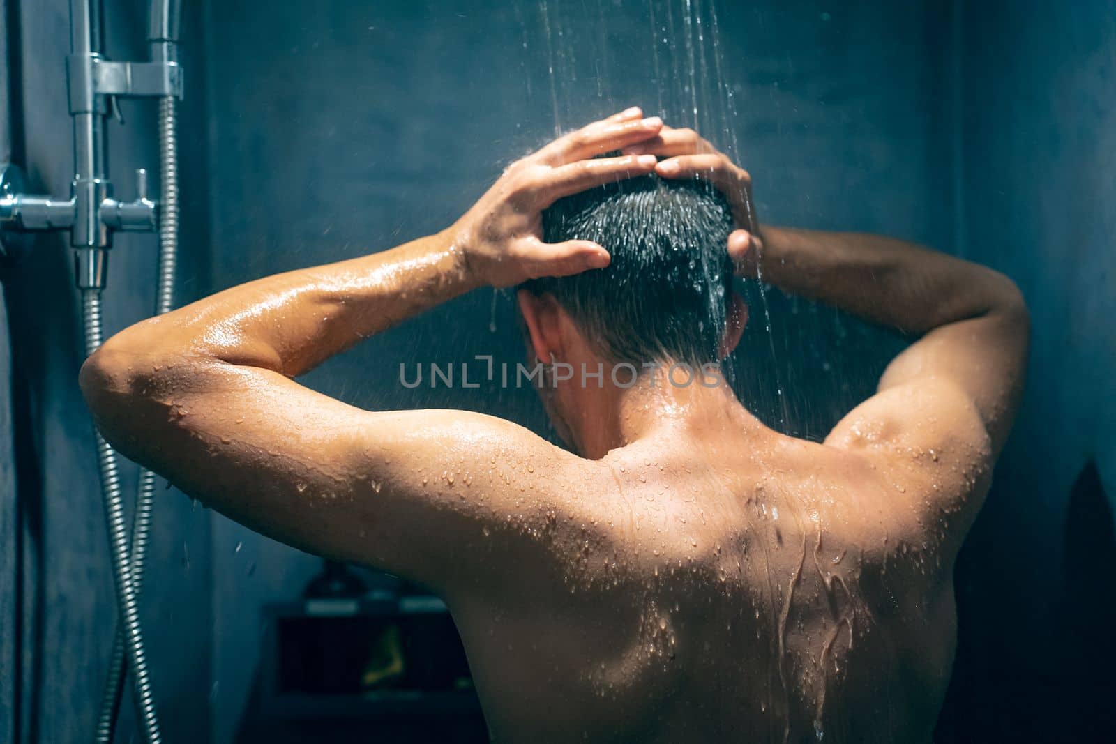 Man taking a shower washing hair with shampoo product under water falling from luxury rain shower head. Morning routine luxury hotel lifestyle guy showering. body care hygiene.