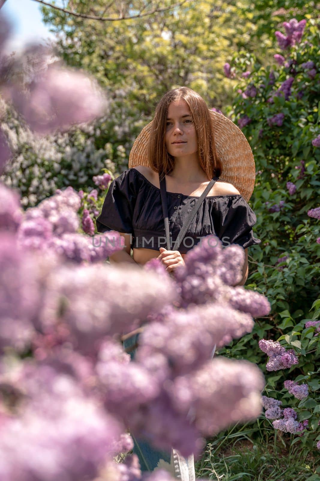 portrait of young woman with long hair outdoors in blooming lilac garden.