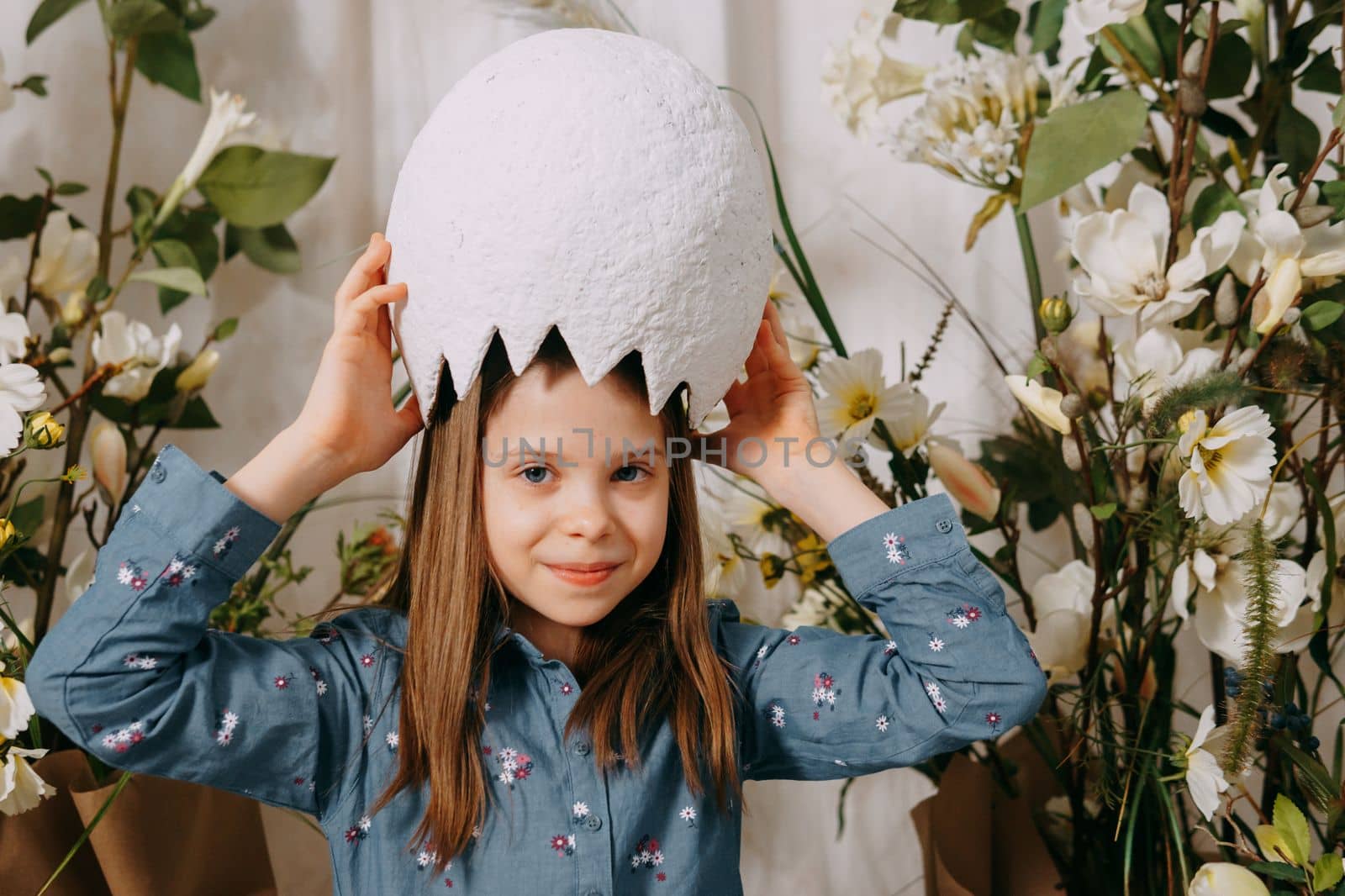 Girl in a beautiful Easter photo zone with flowers, eggs, chickens and Easter bunnies. Happy Easter holiday