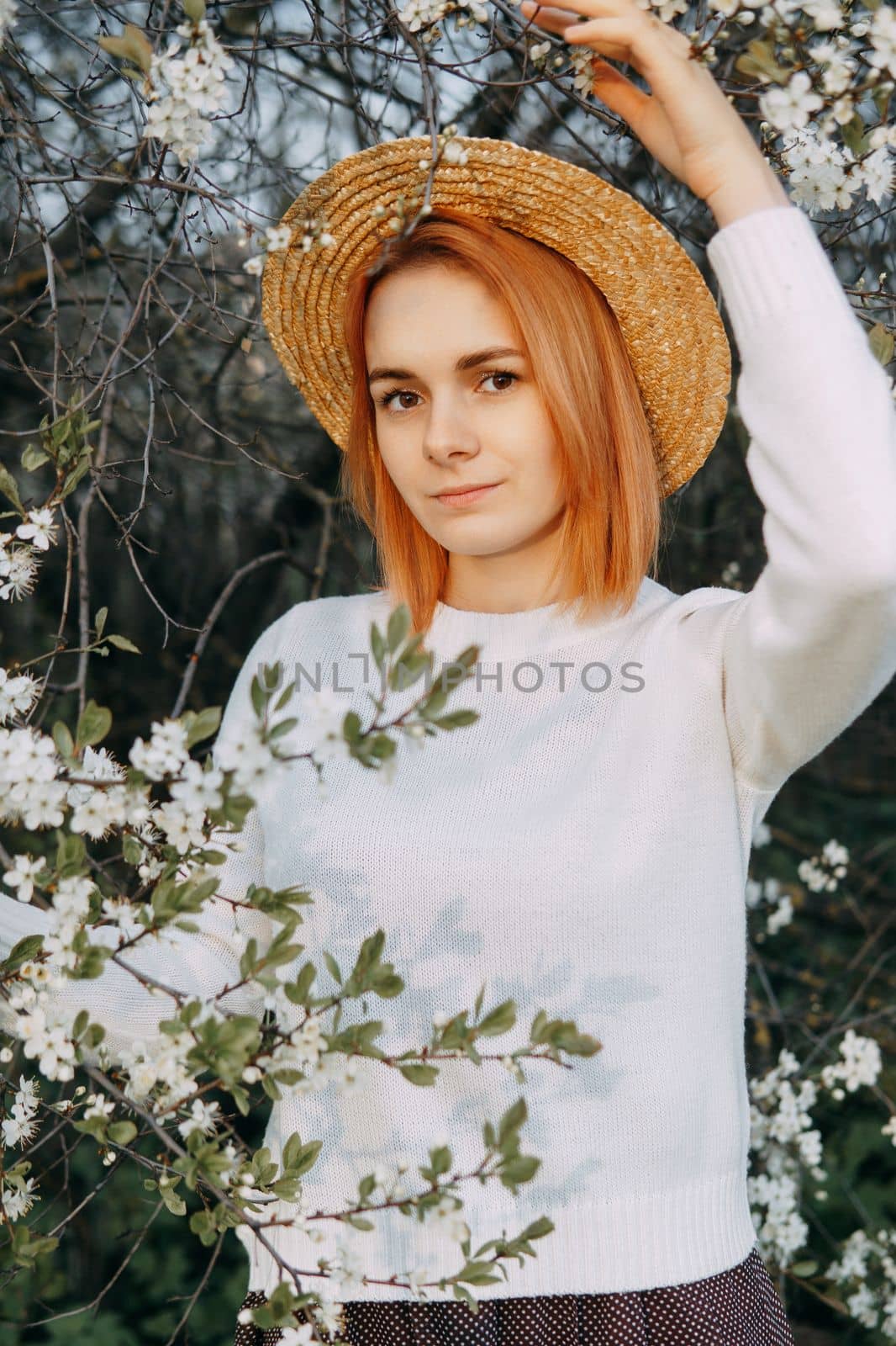 Portrait of a woman in a straw hat in a cherry blossom. Free outdoor recreation, spring blooming garden