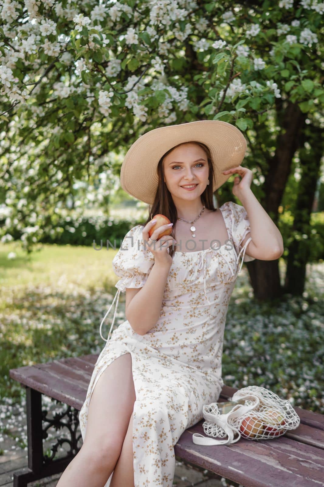 An attractive long-haired woman walks in the spring in the park of blooming apple trees. Spring portrait of a woman