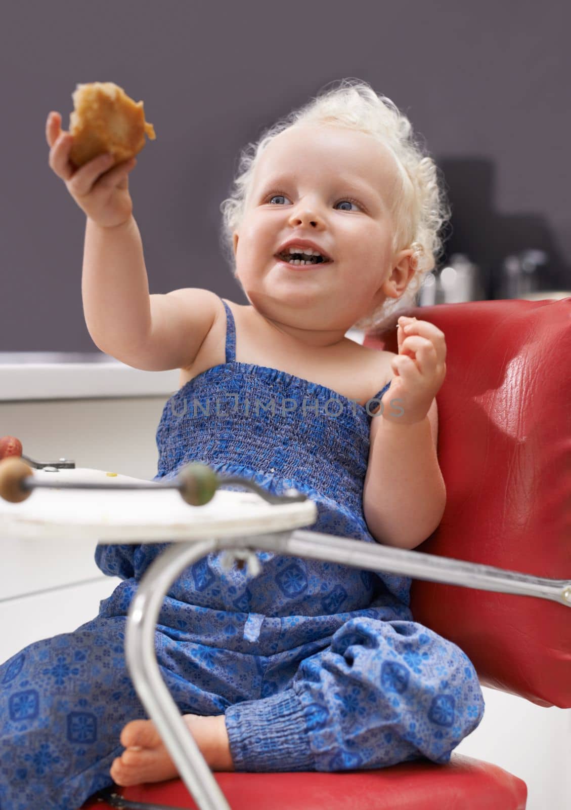 I can feed myself. a cute young baby sitting in a high chair eating