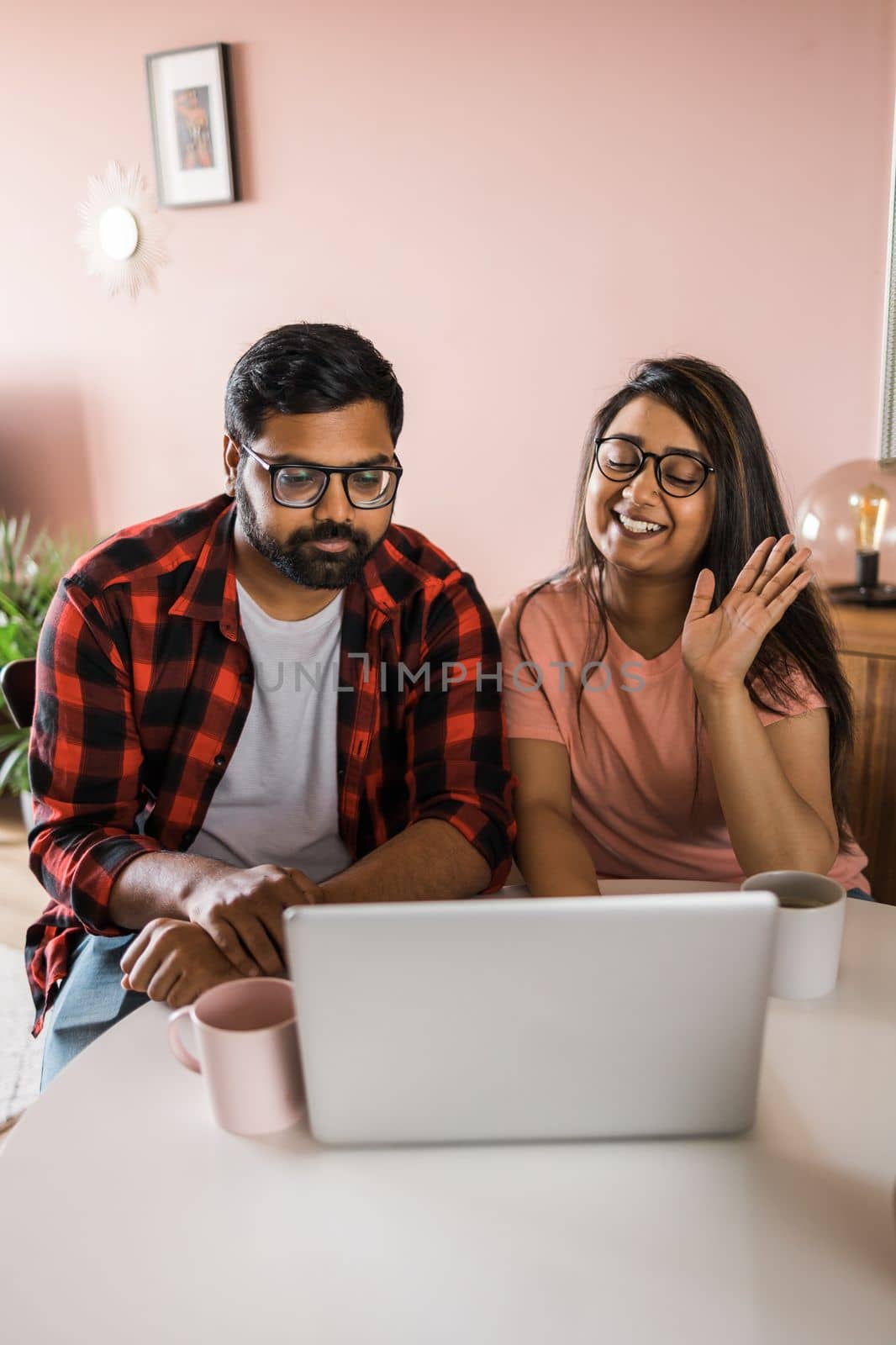 Latino or indian man and woman couple use their laptop in the living room to make video calls. Video call and online chat with family by Satura86