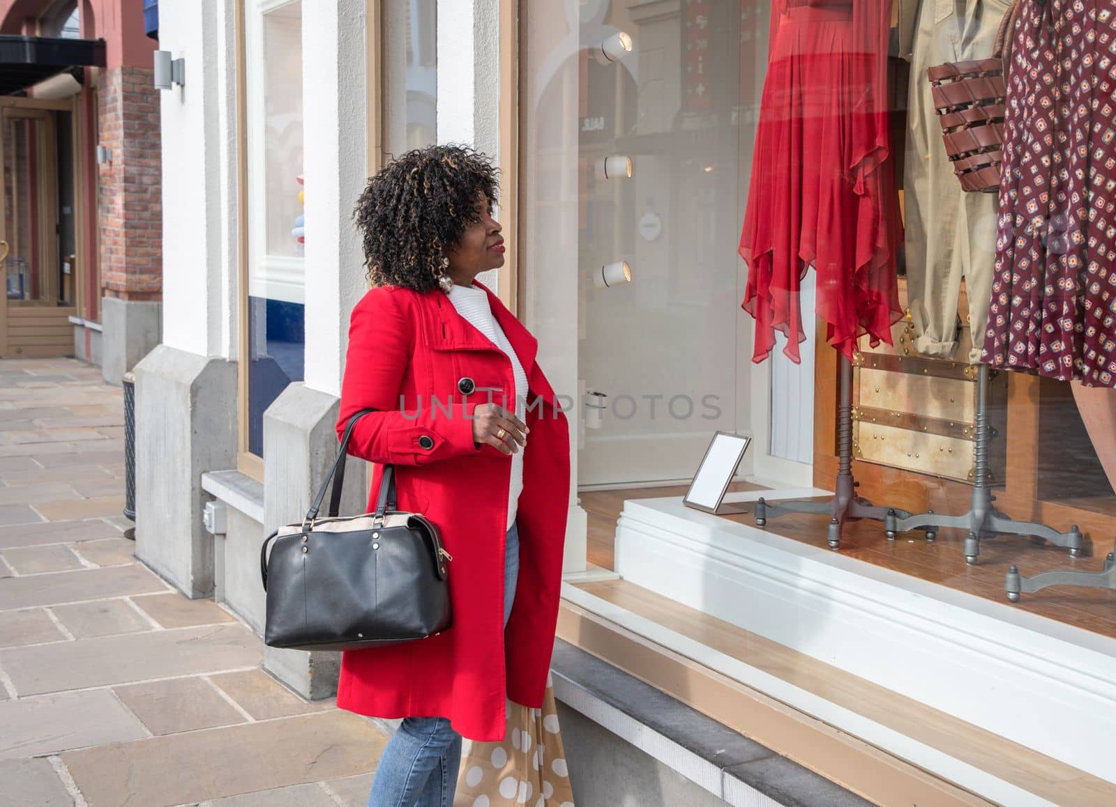 curvy african american woman with shopping bags standing on the street by KaterinaDalemans