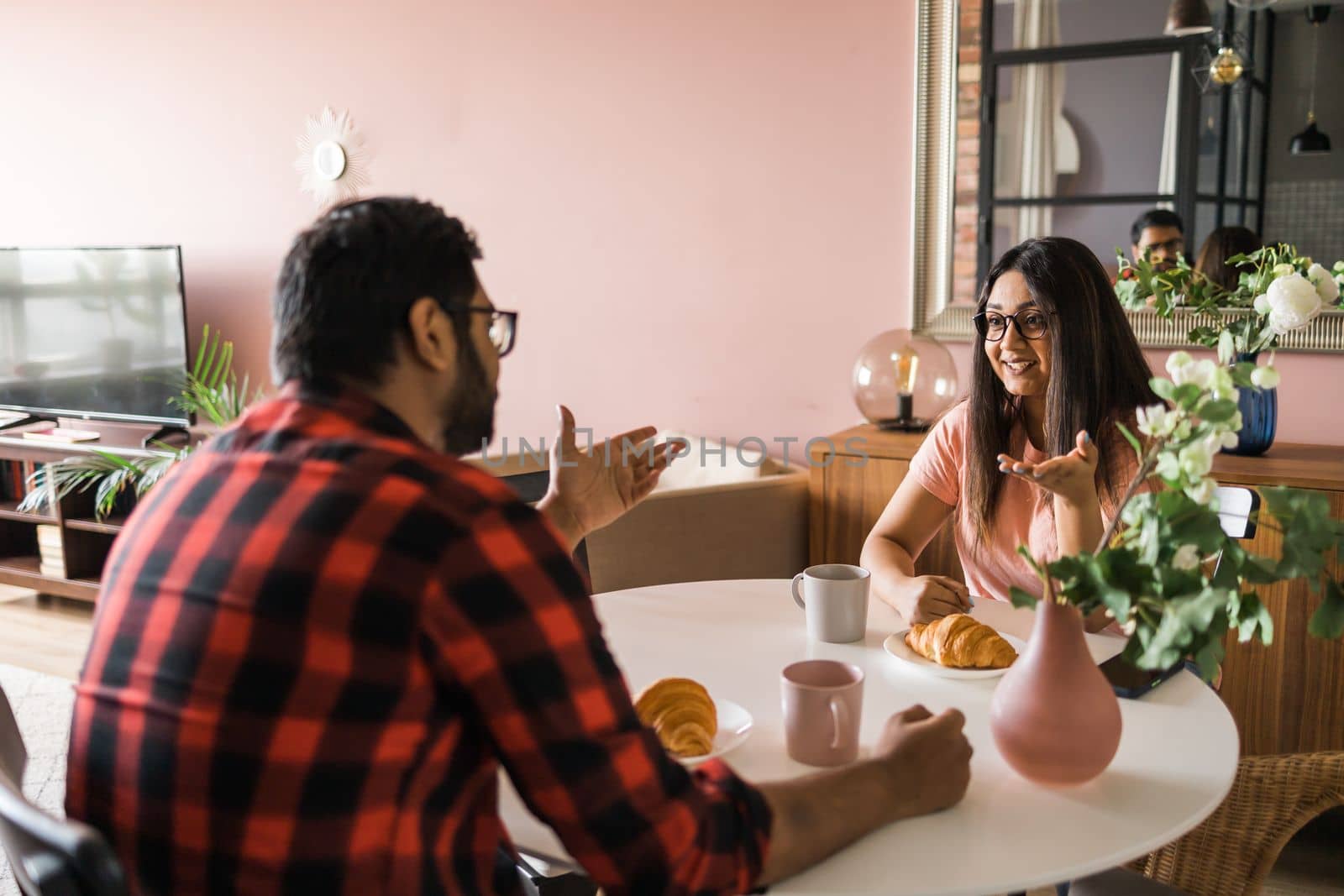 Young diverse loving couple eating croissant and talks together at home in breakfast time. Communication and relationship concept by Satura86