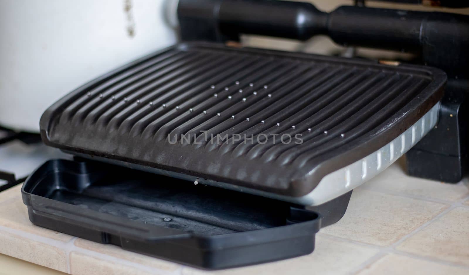 Black electric grill grate, textured background. The surface of the electric grill. Pollution of the surface of the electric stove. Close-up of a home electric grill, in the kitchen. BBQ