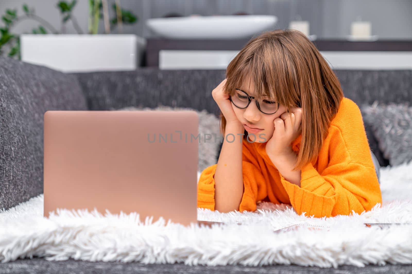disappointed kid looking at laptop at home on sofa. High quality photo