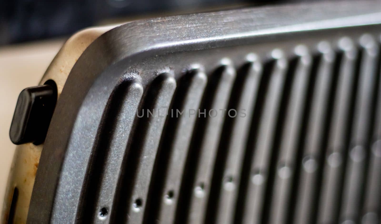 Black electric grill grate, textured background. The surface of the electric grill. Pollution of the surface of the electric stove. Close-up of a home electric grill, in the kitchen. BBQ