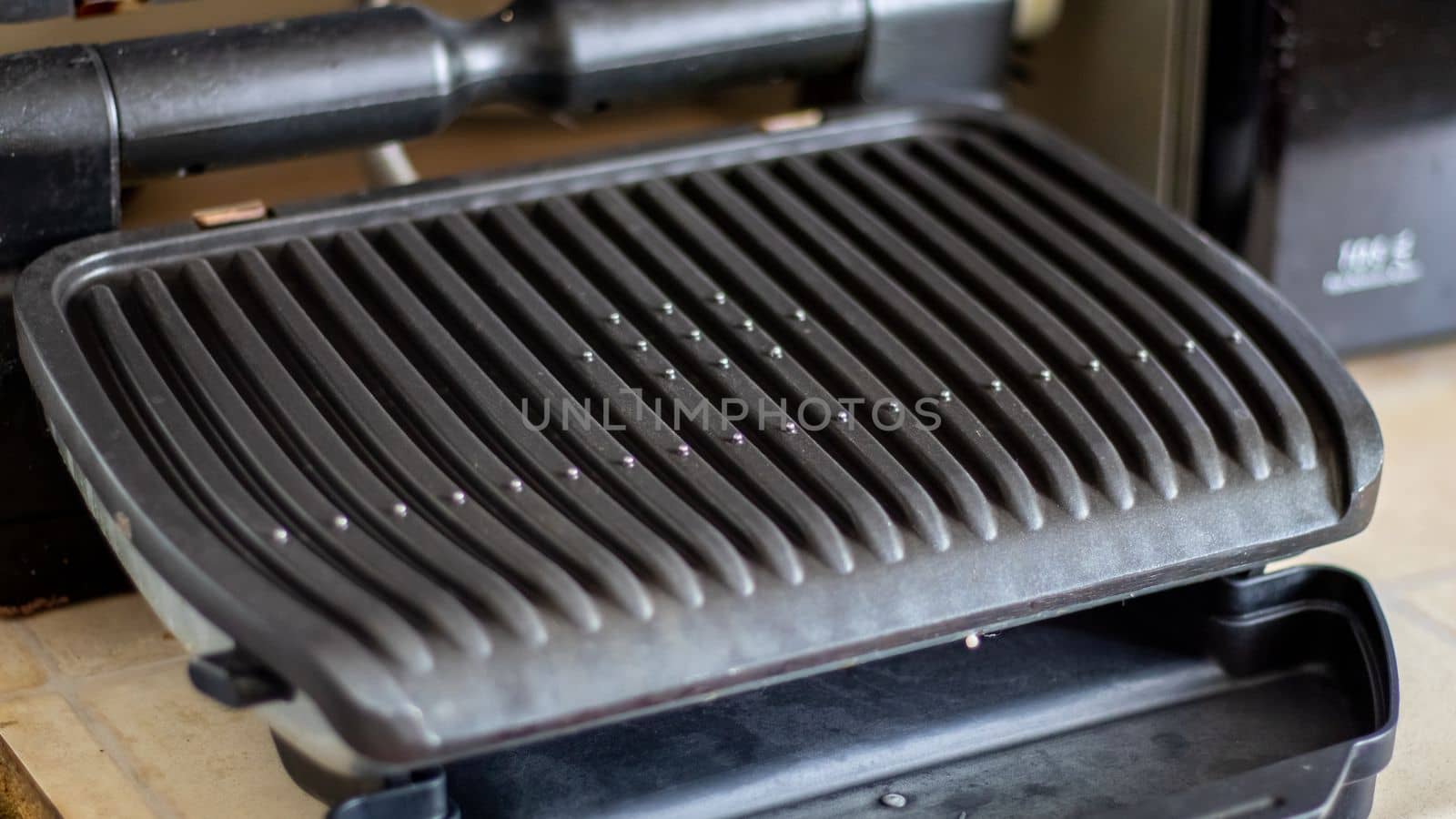 Black electric grill grate, textured background. The surface of the electric grill. Pollution of the surface of the electric stove. Close-up of a home electric grill, in the kitchen. BBQ