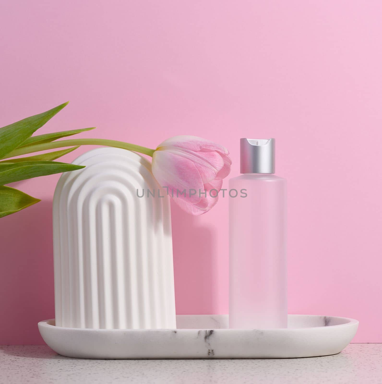 White plastic transparent bottle for liquid cosmetics on a pink background