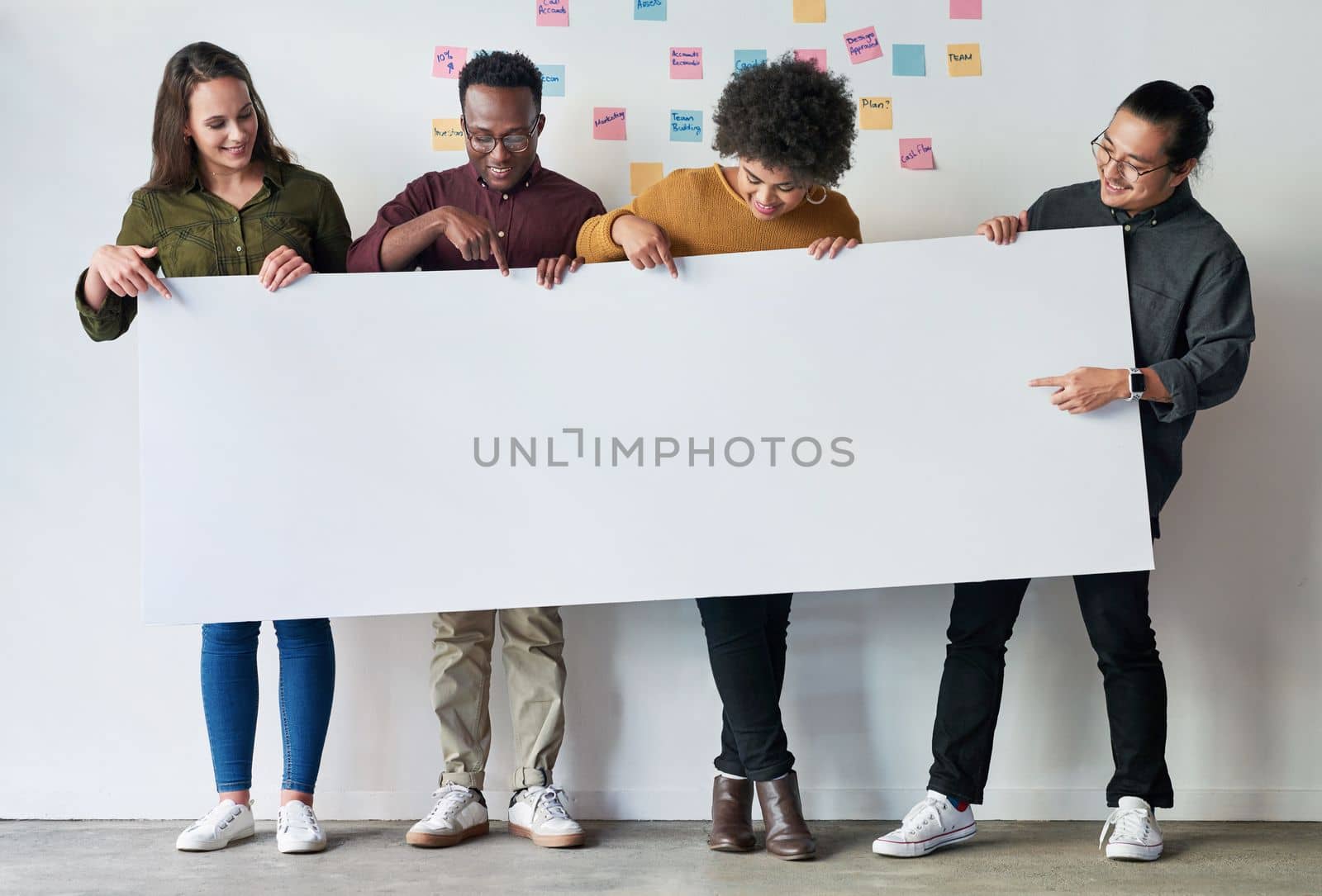 Read the following statement. Full length shot of a group of of young businesspeople holding a placard together at work