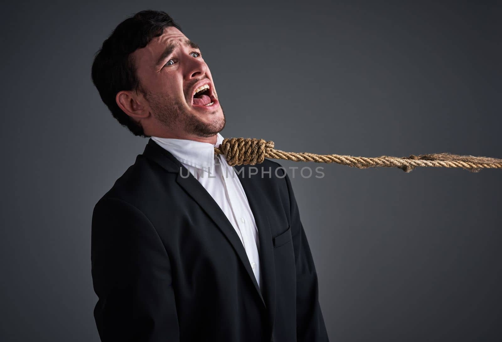 Is stress killing your career. Studio shot of a young businessman being pulled by a hangmans noose against a gray background
