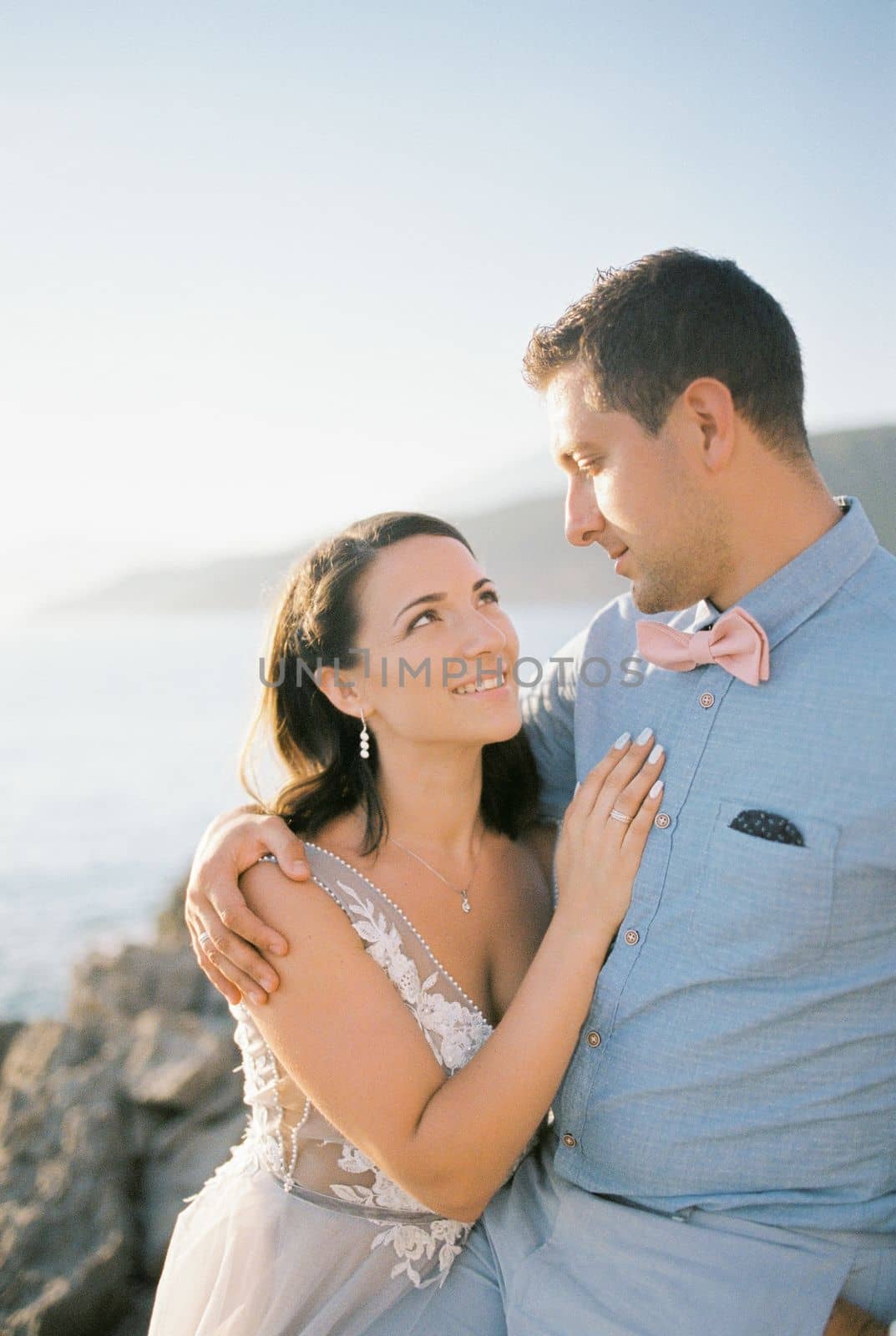 Bride and groom hugging on a rock by the sea. High quality photo