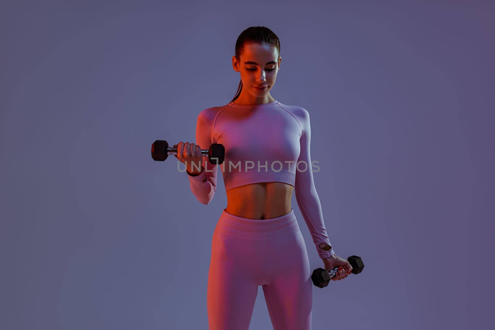 Woman doing exercises with dumbbells on studio background . Sport and healthy lifestyle