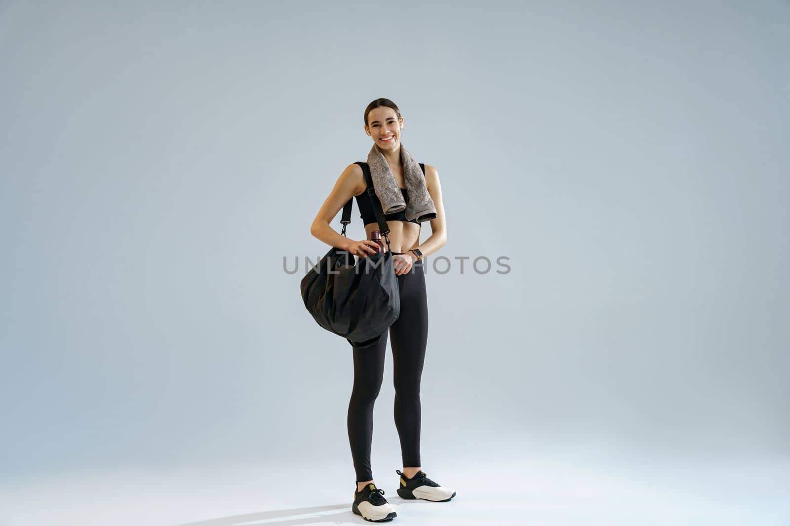 Woman wearing sportswear with sports bag after training on studio background. High quality photo