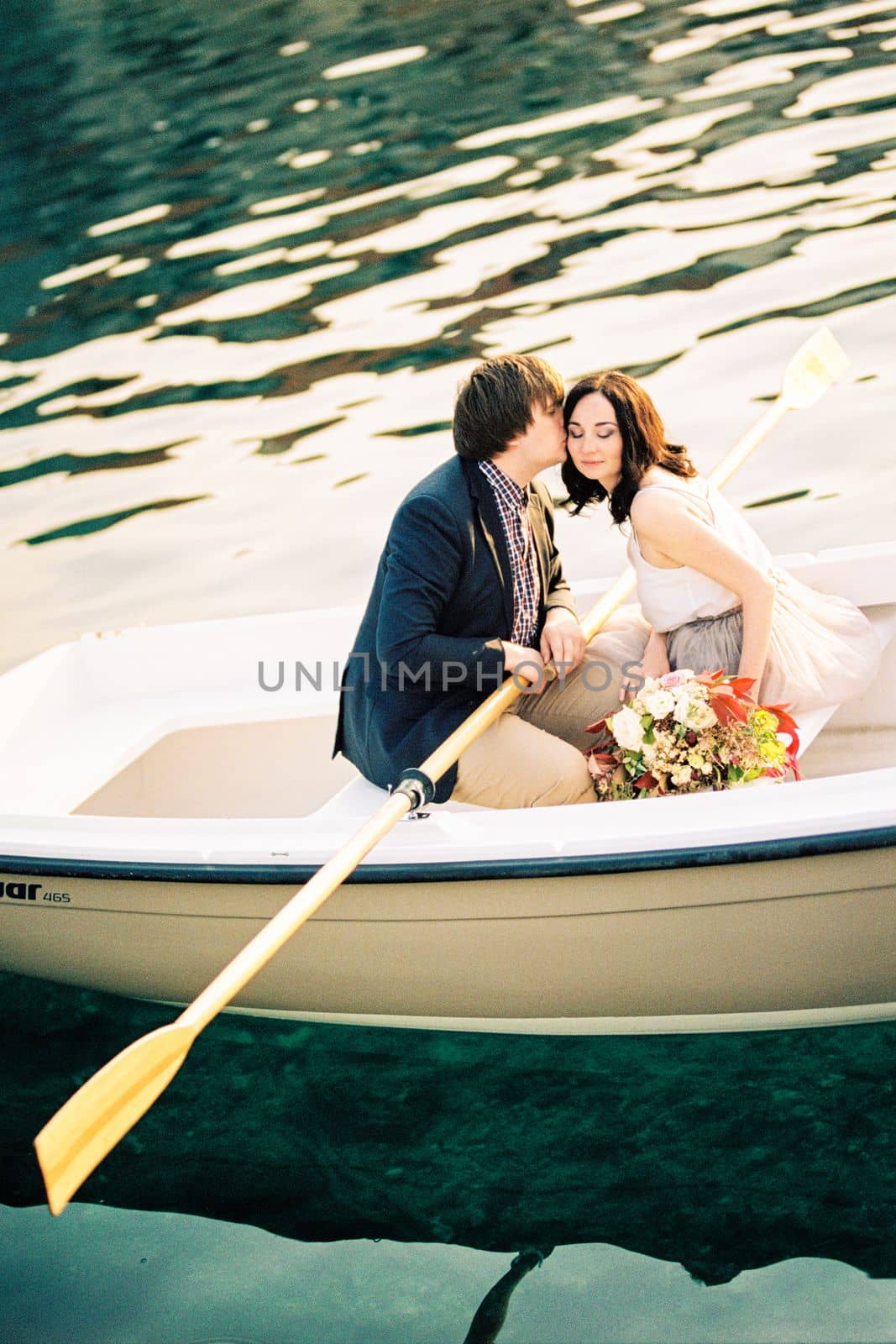 Man kisses woman on the cheek while sitting in a boat with oars. High quality photo