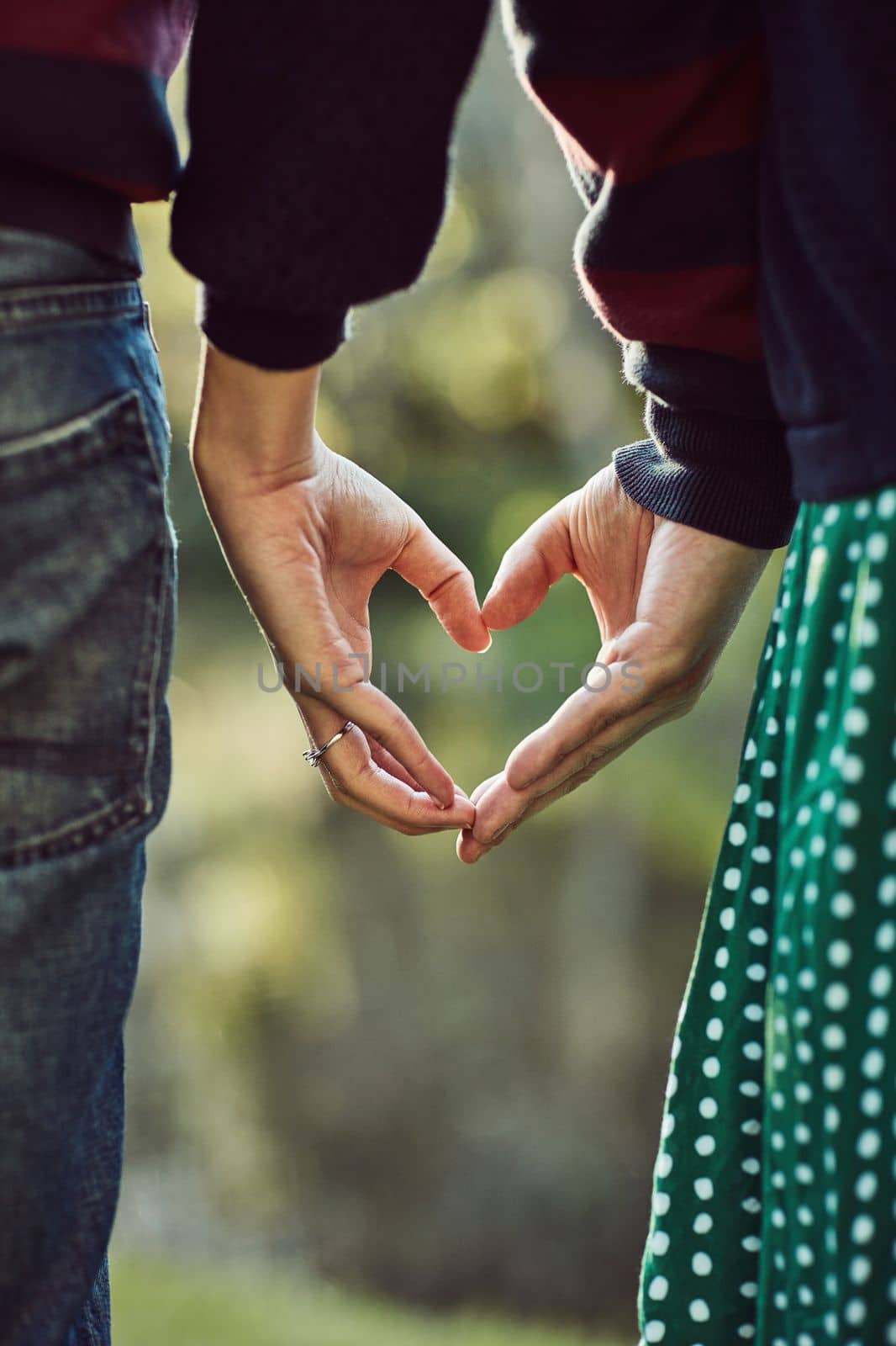 We believe in love. a couple making a heart gesture with their hands outdoors