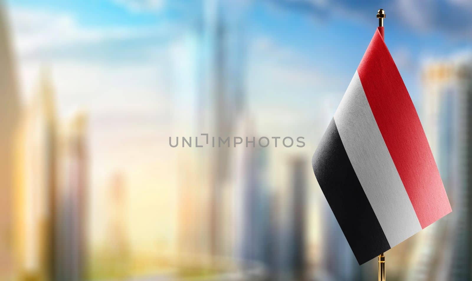 Small flags of the Yemen on an abstract blurry background.