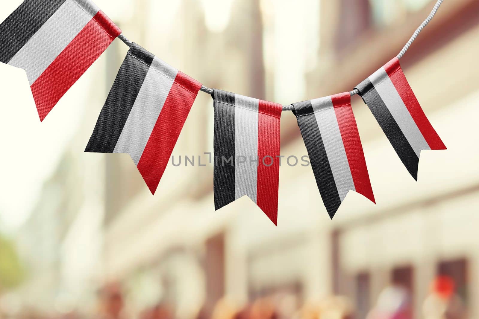 A garland of Yemen national flags on an abstract blurred background.