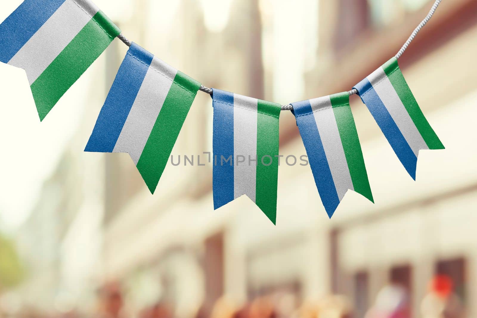 A garland of Sierra Leone national flags on an abstract blurred background by butenkow