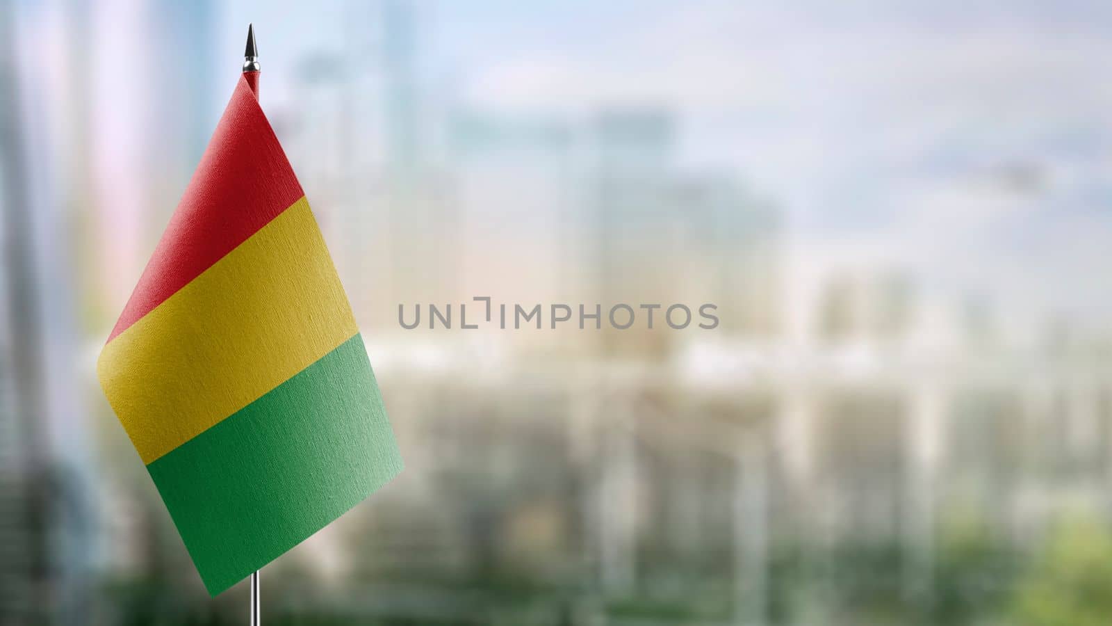 Small flags of the Guinea on an abstract blurry background.