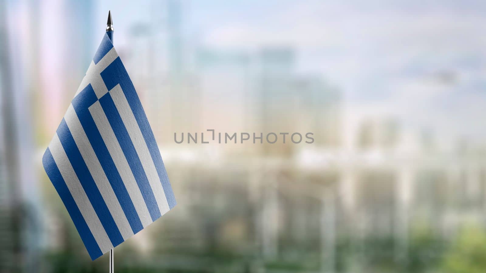 Small flags of the Greece on an abstract blurry background.