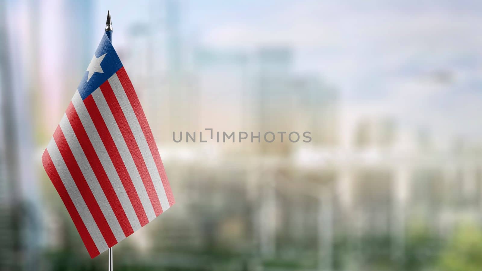 Small flags of the Liberia on an abstract blurry background.