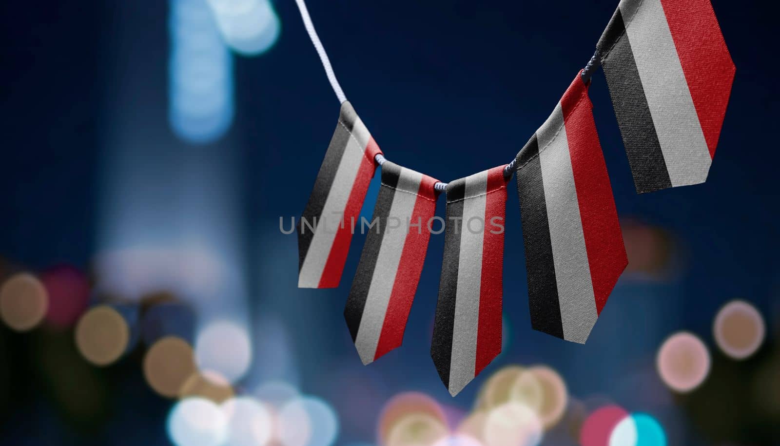 A garland of Yemen national flags on an abstract blurred background.