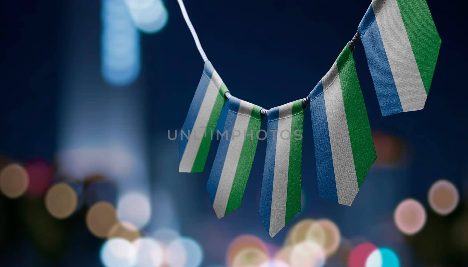 A garland of Sierra Leone national flags on an abstract blurred background.
