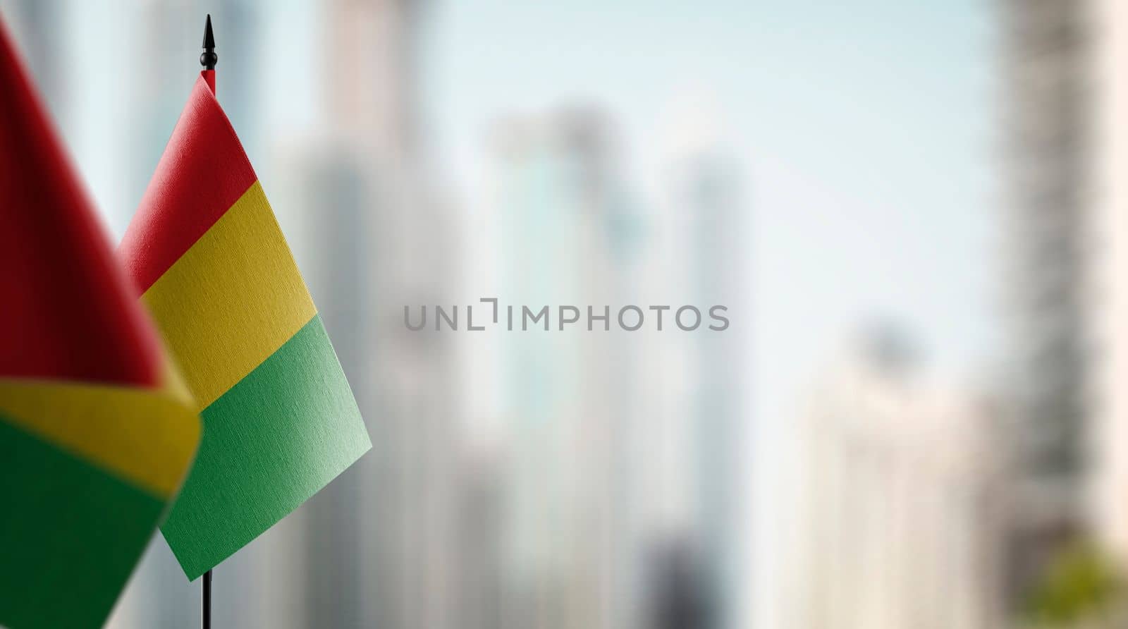 Small flags of the Guinea on an abstract blurry background.