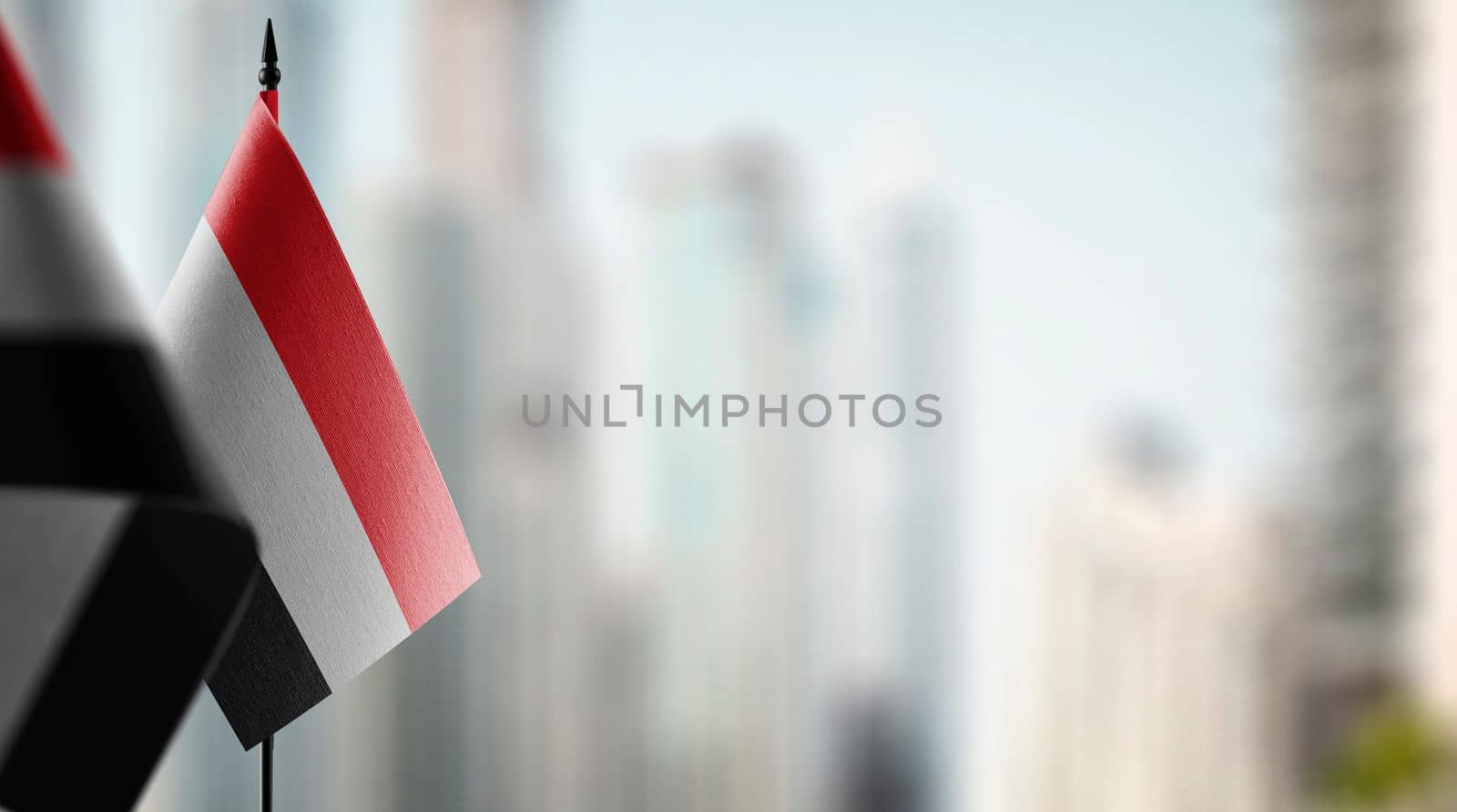 Small flags of the Yemen on an abstract blurry background.