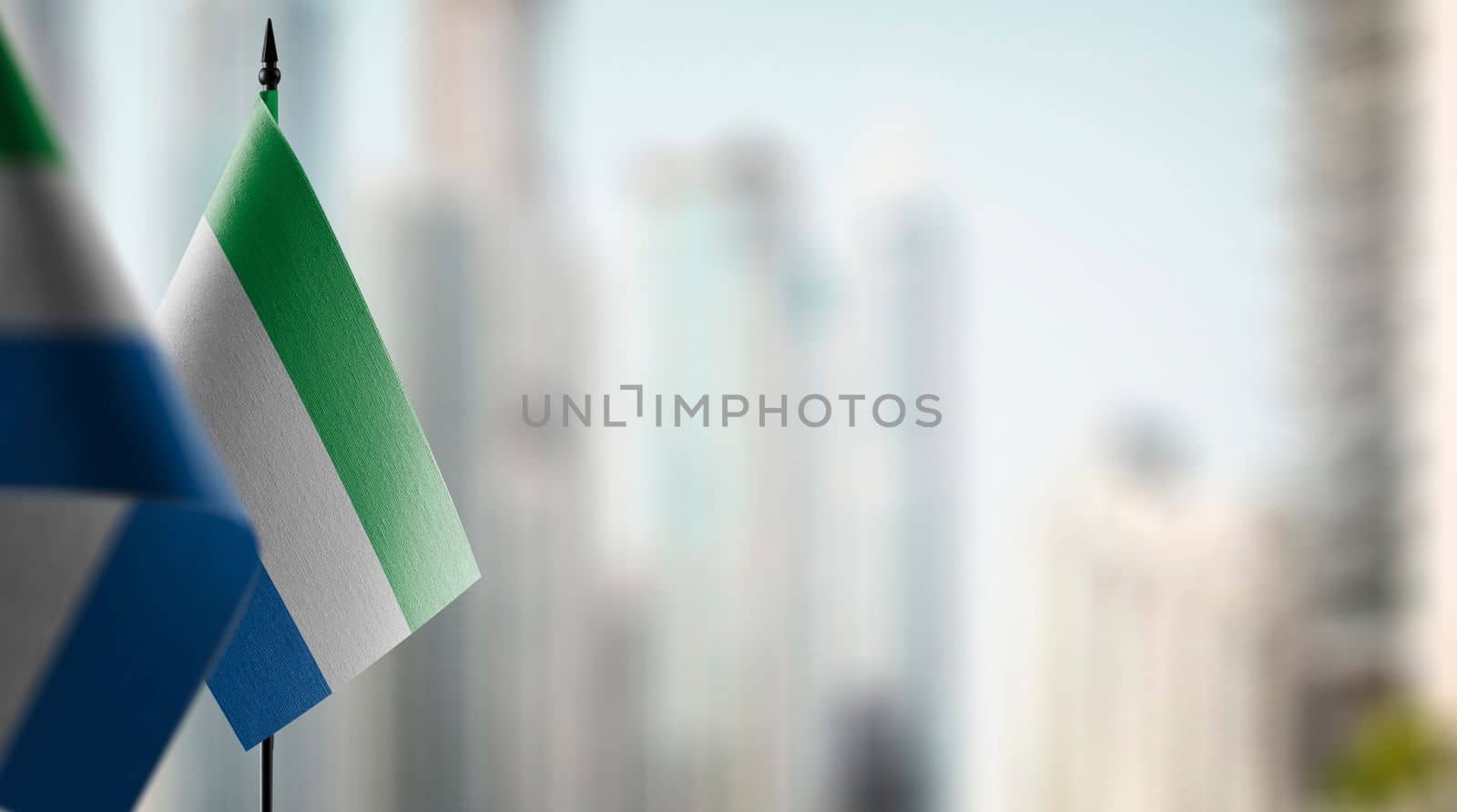 Small flags of the Sierra Leone on an abstract blurry background.