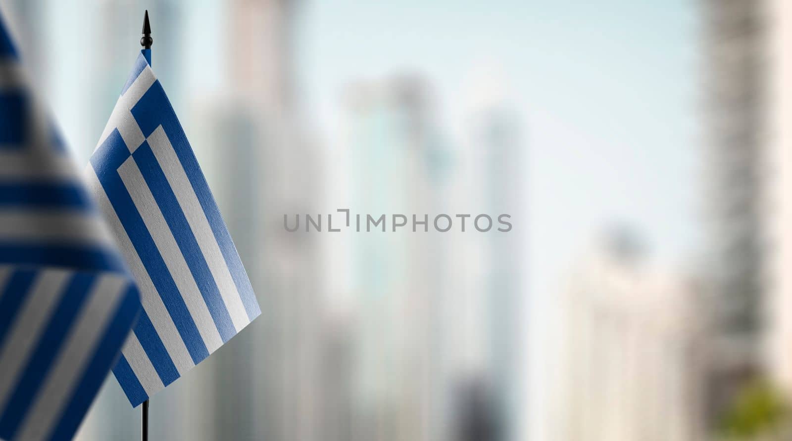 Small flags of the Greece on an abstract blurry background.