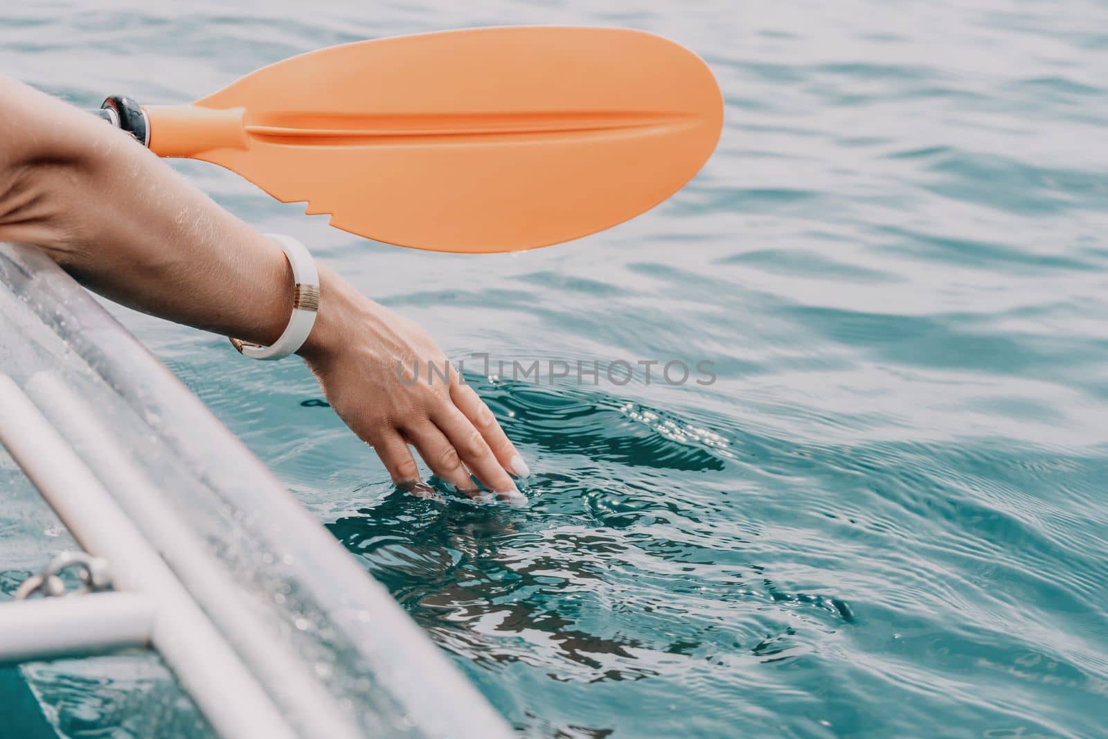 Woman in kayak back view. Happy young woman with long hair floating in transparent kayak on the crystal clear sea. Summer holiday vacation and cheerful female people relaxing having fun on the boat by panophotograph