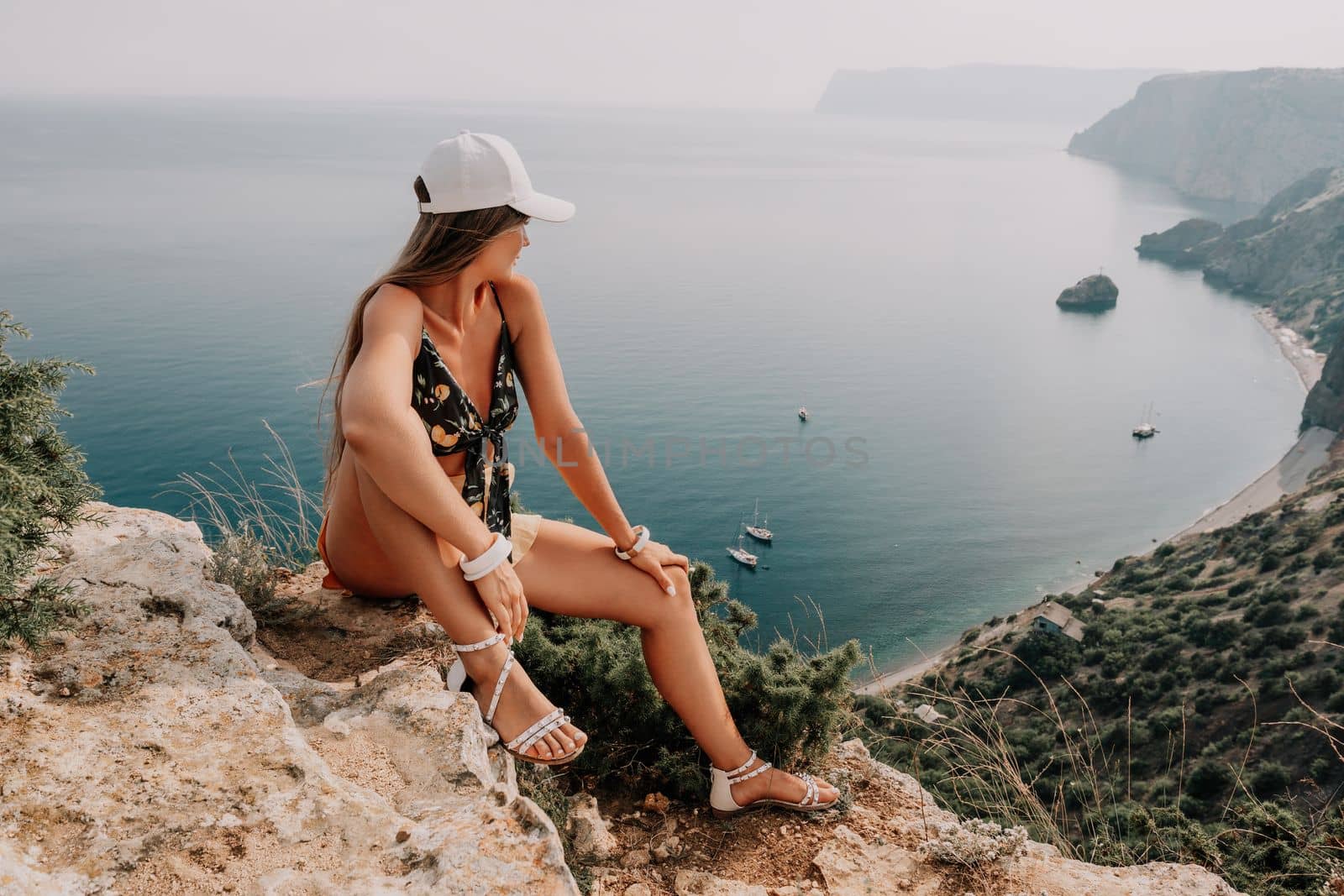 Woman travel sea. Happy tourist taking picture outdoors for memories. Woman traveler looks at the edge of the cliff on the sea bay of mountains, sharing travel adventure journey.