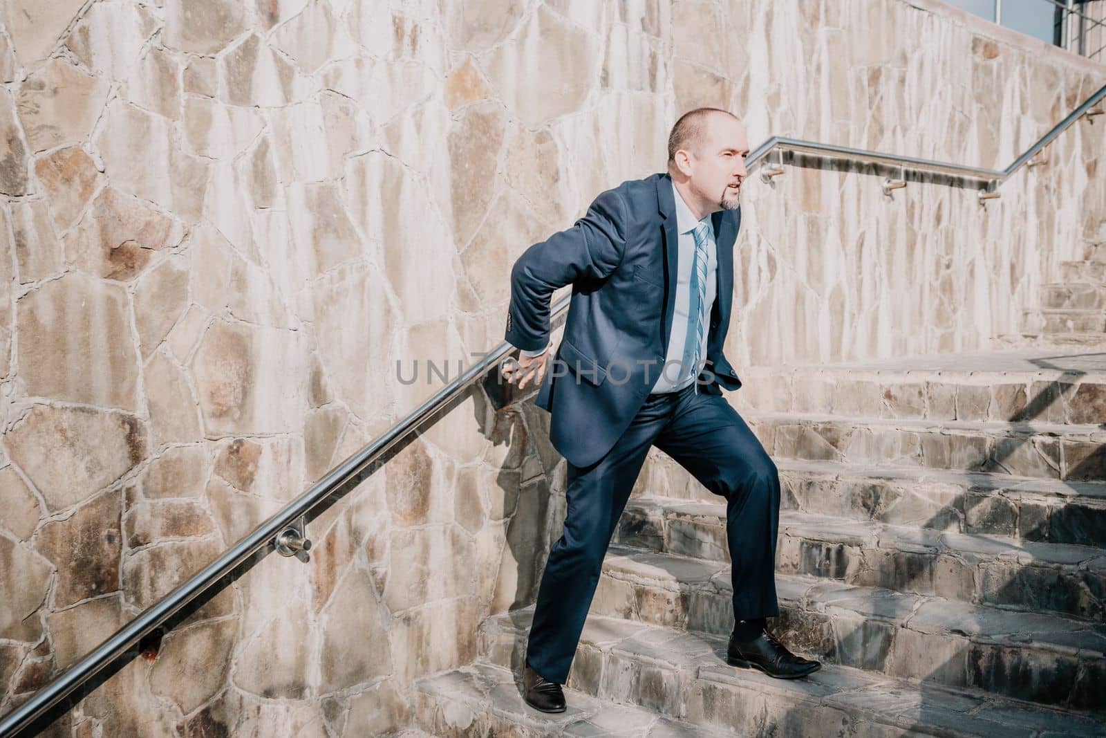 Portrait of a senior professional man in a suit with various problems. A middle-aged businessman with a briefcase descends the stairs.