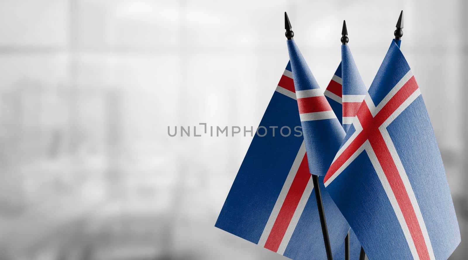 Small flags of the Iceland on an abstract blurry background.