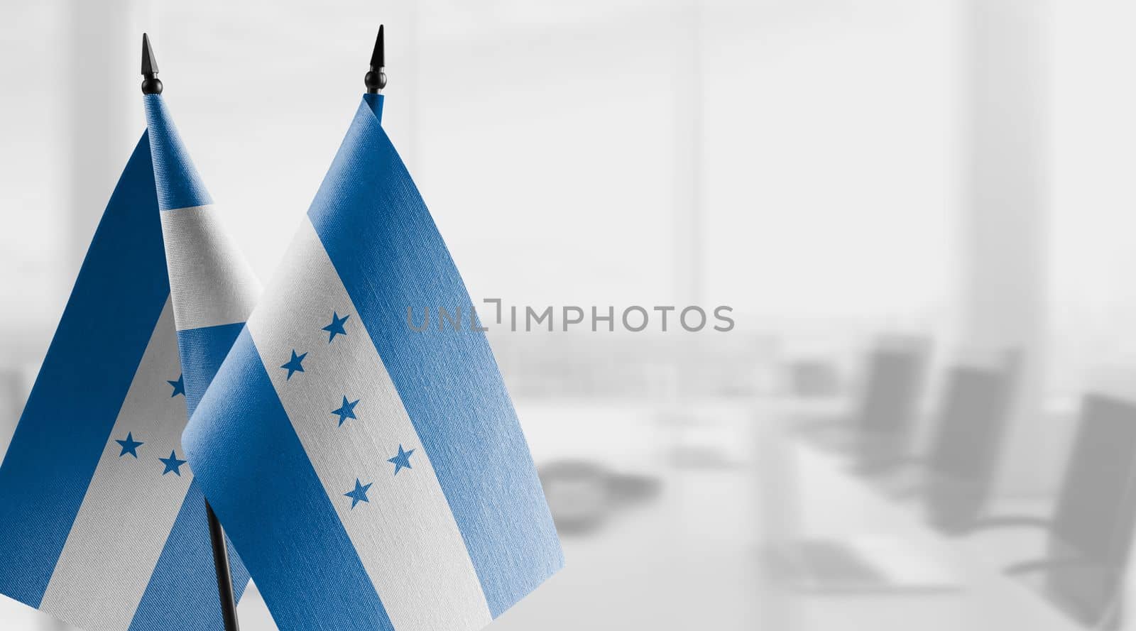 Small flags of the Honduras on an abstract blurry background.