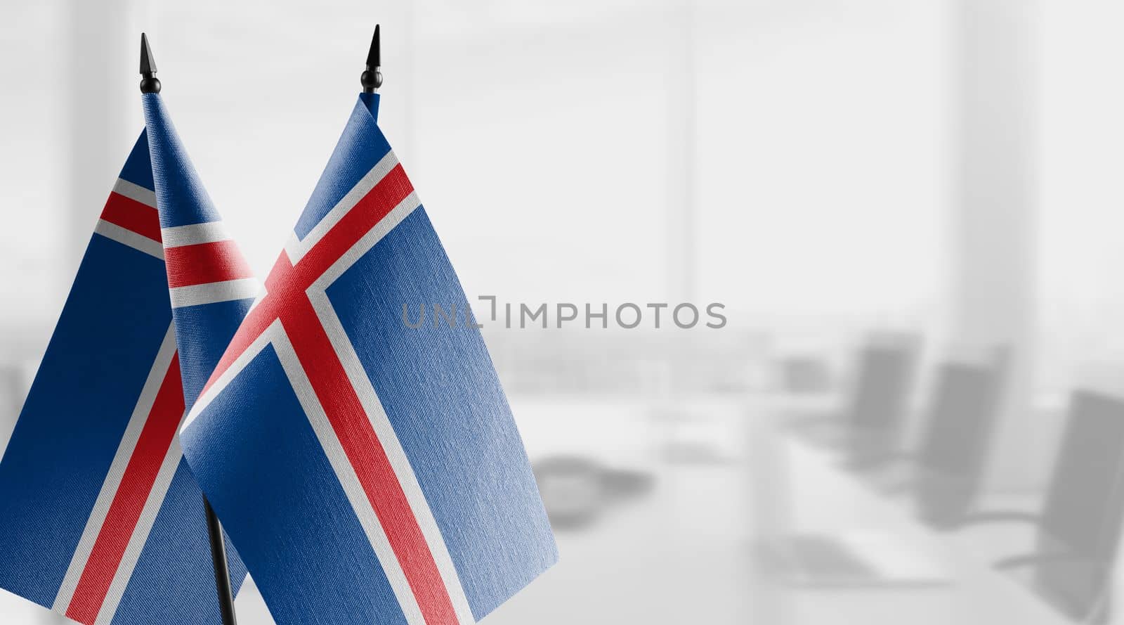 Small flags of the Iceland on an abstract blurry background.