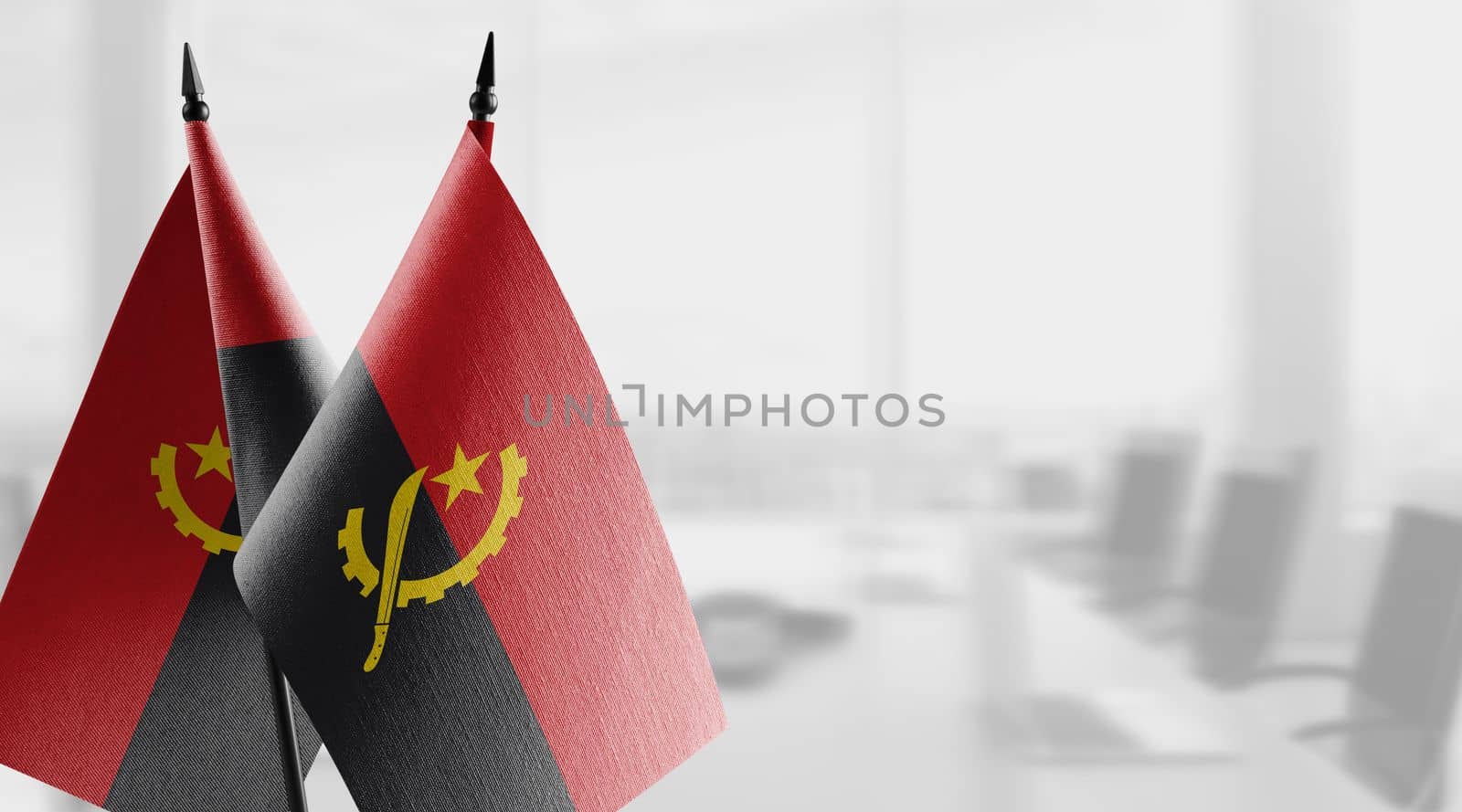 A small Angola flag on an abstract blurry background by butenkow