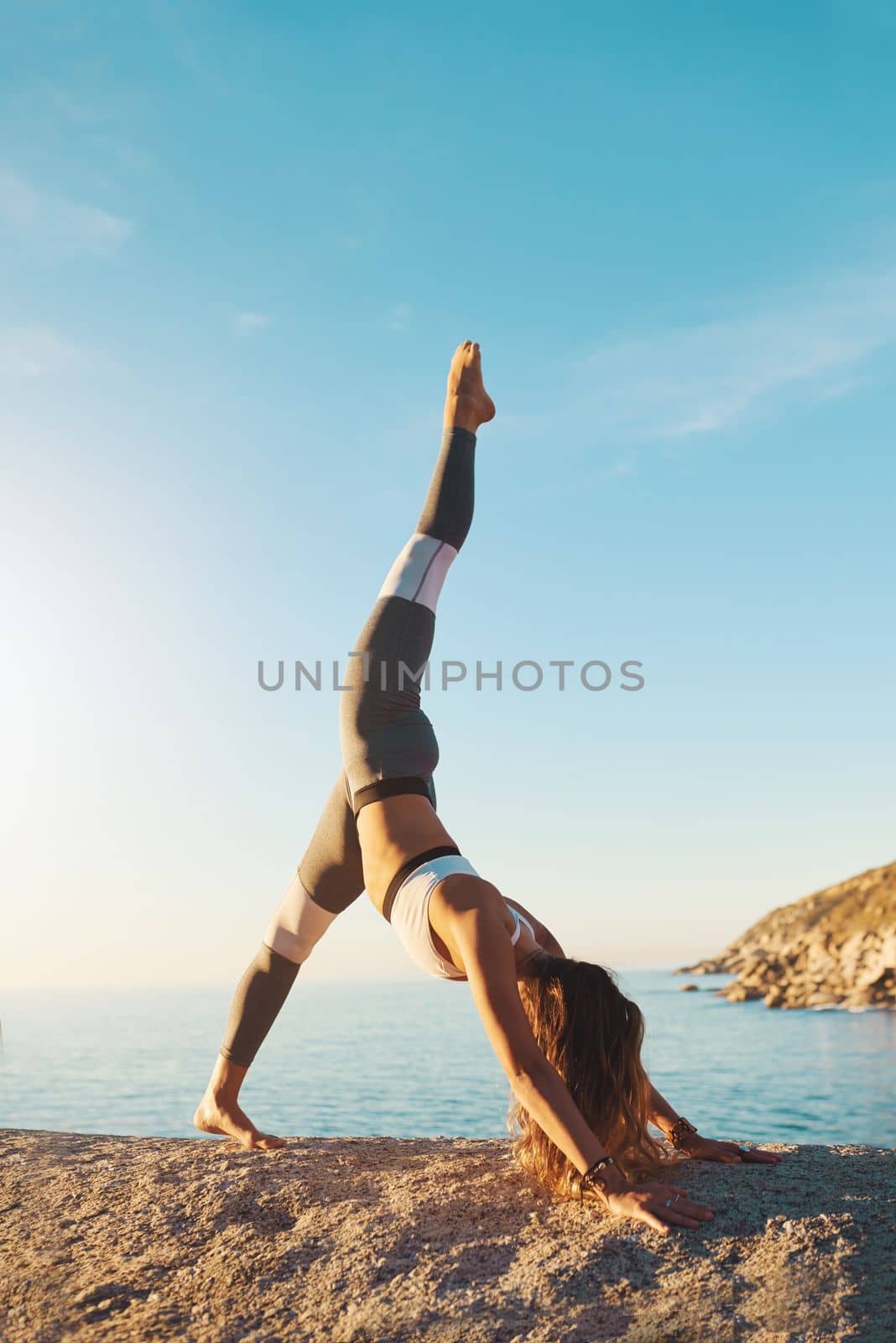 Yoga does wonders. an athletic young woman practicing yoga on the beach. by YuriArcurs